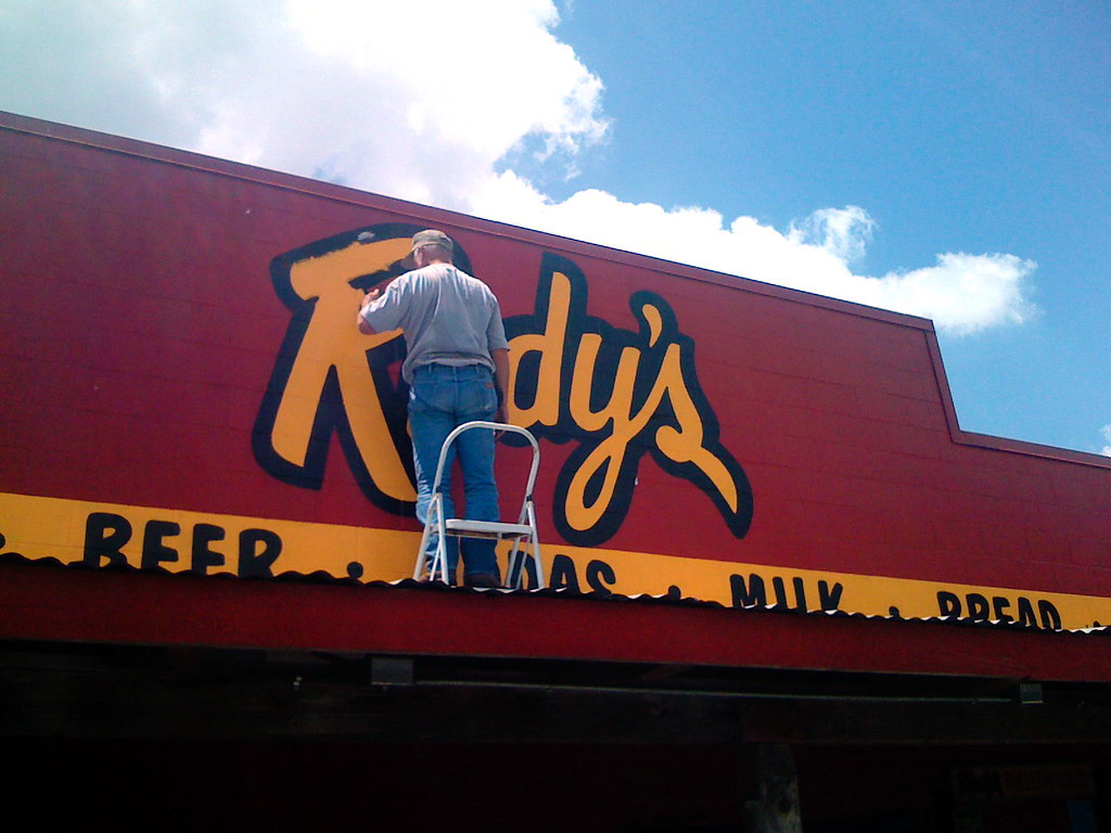 touching up the hand-painted sign at rudy's barbeque